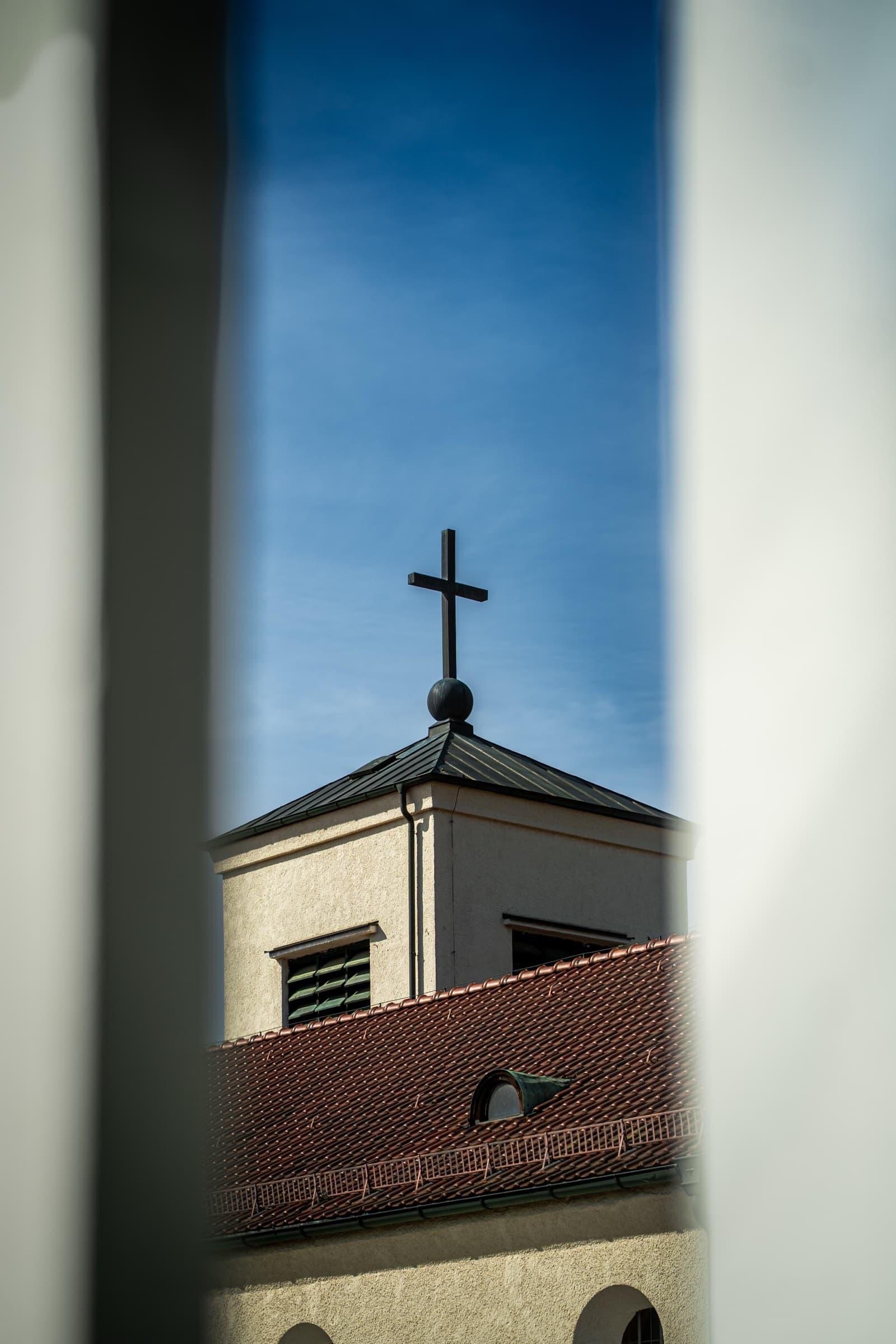 Church bell tower with cross, glimpsed between walls