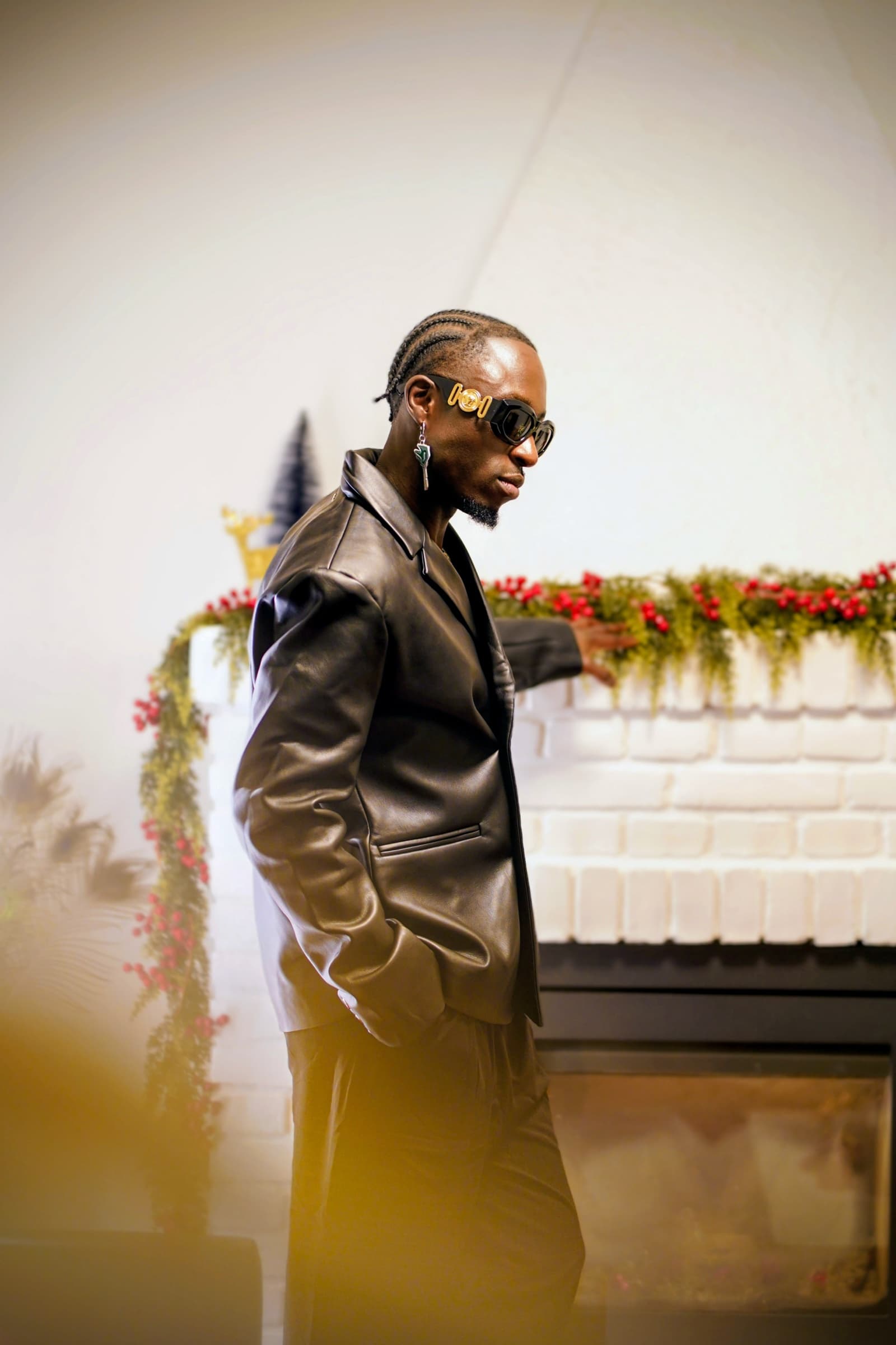 Black leather suit and gold sunglasses by a festive fireplace