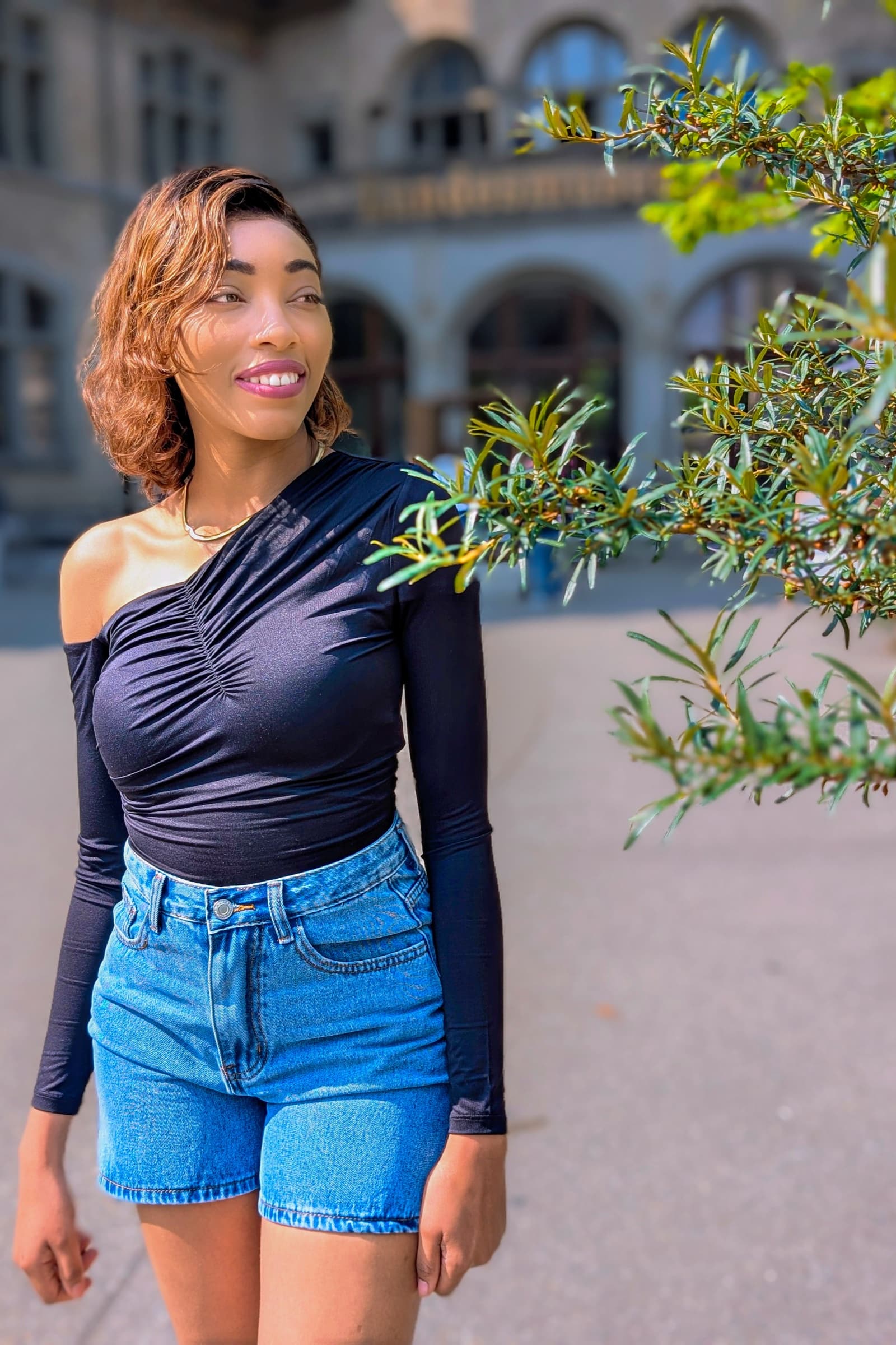 Black off-shoulder top and denim shorts, palace courtyard
