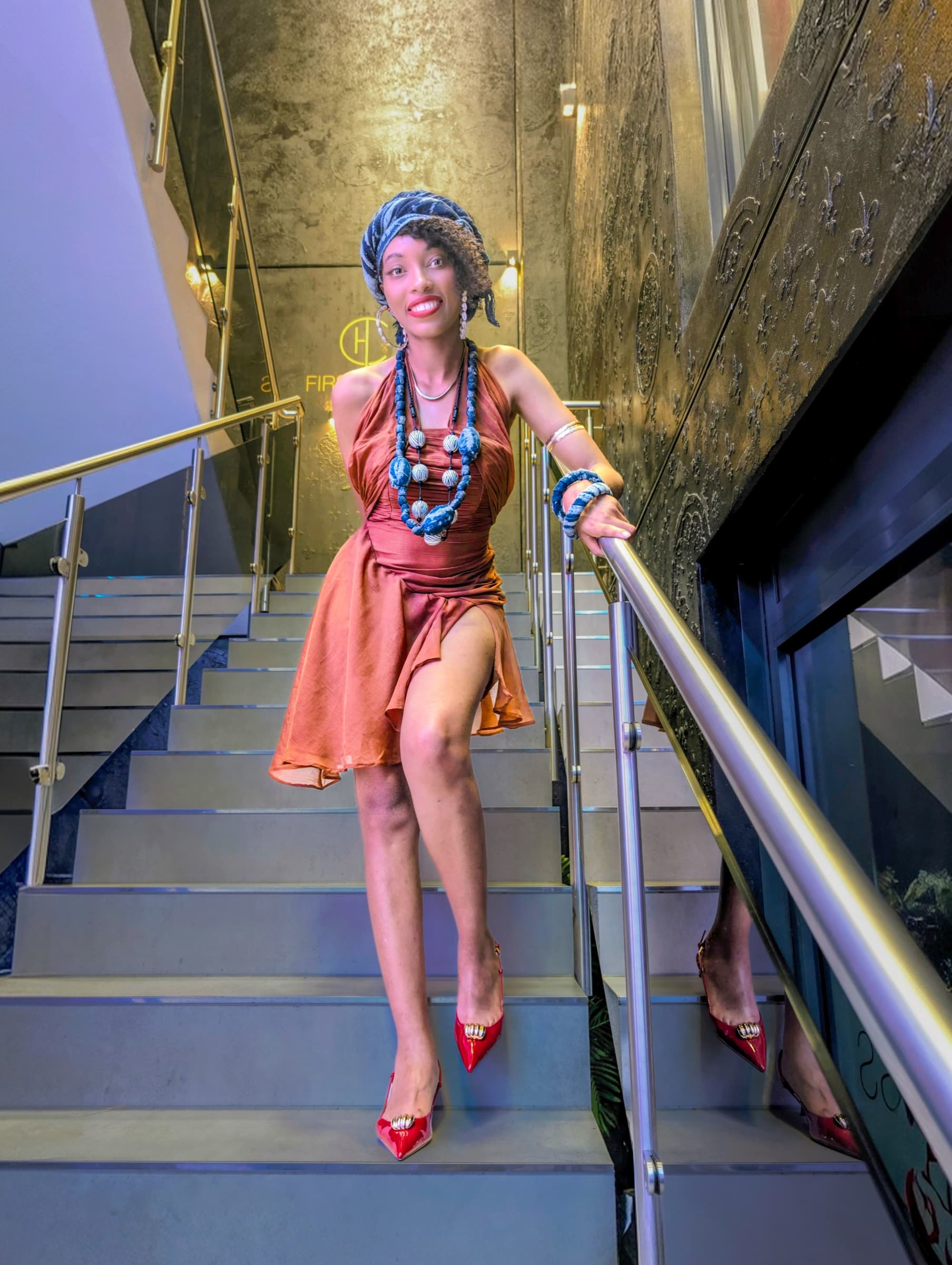 Brown silk dress and headscarf on a gold staircase