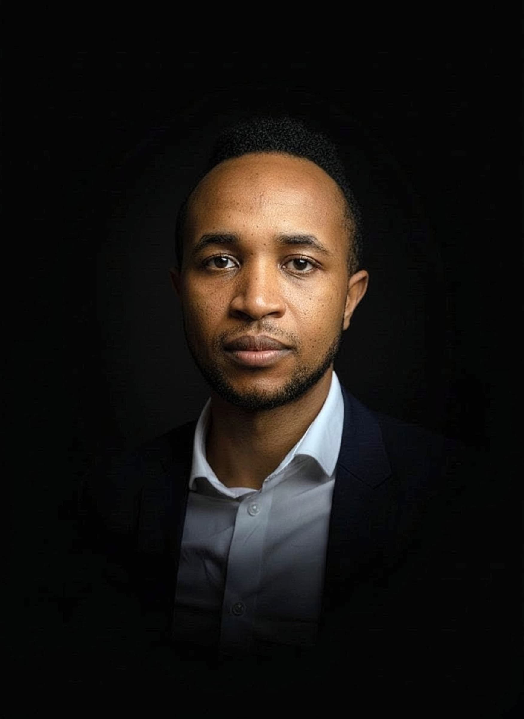 Studio portrait, dark backdrop, suit and white shirt